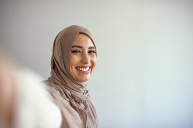 Kafkasyalı Müslüman bir kadın selfie çekiyor. Fularlı mutlu güzel kadın akıllı telefon kullanarak kendi fotoğrafını çekiyor. Genç, güzel ve modern Müslüman bir kadın selfie çekiyor.. 