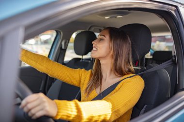 Güzel kadın sürücü dikiz aynasını ayarlıyor ve kendine bakıyor. Dikiz aynasını ayarlıyorum. Kadın dikiz aynasını eliyle ayarlıyor. Mutlu genç kadın sürücü dikiz aynasını ayarlıyor.