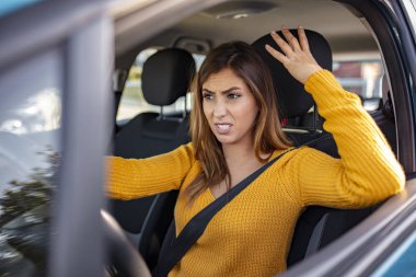 Stressed woman driver. Young businesswoman driving a car while being tired from work. Distraught mid adult woman driving a car. Displeased young stressed angry pissed off woman driving car annoyed by heavy traffic