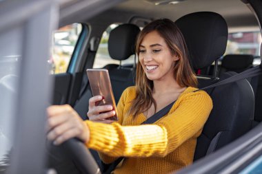 Arabadaki Kadın Cep Telefonu. Genç kız trafik sıkışıklığında mesaj atıyor. Genç bayan sürücü direksiyonda akıllı telefon kullanıyor. Genç bir kadın, cep telefonuyla arabada, mesajını ya da navigasyonunu kontrol ediyor.