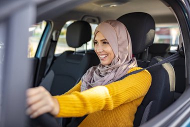 Araba kullanan tesettürlü güzel bir kadın. Orta Doğulu araba kullanan bir kadının portresi, modern bir bej Abaya giyiyor. Emirati kadını araba kullanıyor.. 