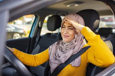 Stressed Muslim woman drive car feeling sad and angry. Distraught mid adult woman driving a car. Displeased young stressed angry pissed off woman driving car annoyed by heavy traffic