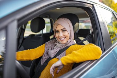 Araba kullanan Arap kadınlar. Genç Müslüman kadın sürücü. Gülümseyen Müslüman kadın aracını kullanıyor. Güzel Müslüman kadın, dişlek gülüşlü araba kullanıyor.. 