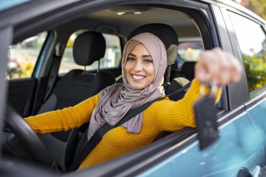 Yeni bir araçta arabanın anahtarını tutan mutlu bir Arap kadını. Müslüman kadın yeni arabasında. Yeni aracın içinde arabanın anahtarını tutan mutlu Arap kadın. Arabada oturan Müslüman Kadın