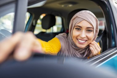 Modern Arap kadın dikiz aynasını ayarlıyor. Orta Doğulu Kadın Araba Kullanıyor, İleriye Bakıyor. Güzel, beyaz, Müslüman bir kadın, araba yaşam tarzı çekiminde hafif başörtüsü takıyor.