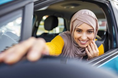 Modern Arap kadın dikiz aynasını ayarlıyor. Orta Doğulu Kadın Araba Kullanıyor, İleriye Bakıyor. Güzel, beyaz, Müslüman bir kadın, araba yaşam tarzı çekiminde hafif başörtüsü takıyor.
