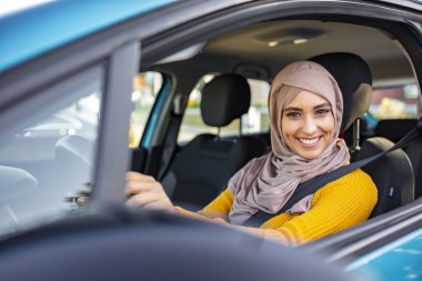 Geleneksel gülümseyen Arap kadın yeni araba deniyor. Arabasını süren genç müslüman bir kadının portresi. Araba kullanan Arap kadınlar.
