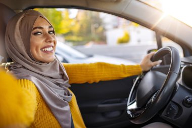 Güzel Müslüman kadın arabada selfie çekiyor. Gülümseyen genç Müslüman kadın arabada akıllı telefon kamerasıyla selfie çekiyor. Tatil ve turizm konsepti