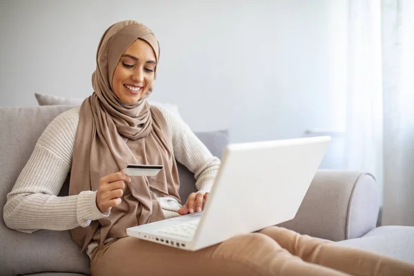 コンテンツアラブ女性ショッピング自宅でオンライン オンラインショッピング ラップトップでクレジットカードを示す美しい若いイスラム教徒の女性 笑顔若いイスラム教徒の女の子オンラインショッピングに家 — ストック写真