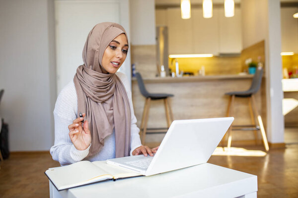Muslim woman working with computer at home. Muslim woman working with computer in the room , writing paper. Confidence pretty muslim woman Business and finance concepts.