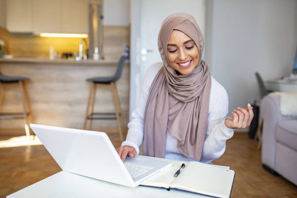 Pretty woman wearing hijab in front of laptop search and doing office work, business, finance and workstation concept. Arabian Businesswoman working at home. Dedication and technology. Islamic woman sitting and using laptop