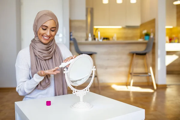 鏡を見て顔のクリームをかける美しいイスラム教徒の女性 鏡の中で顔を見ているヒジャーブを持つイスラム教徒の女性 保湿クリーム スキンケア 美容を適用する笑顔のイスラム教徒の女性 — ストック写真