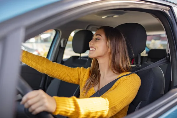 Beautiful female Driver adjusting the Rear Mirror looking at herself. Adjusting the rear view mirror. Woman adjusts the rear view mirror with her hand. Happy young woman driver looking adjusting rear view car mirror