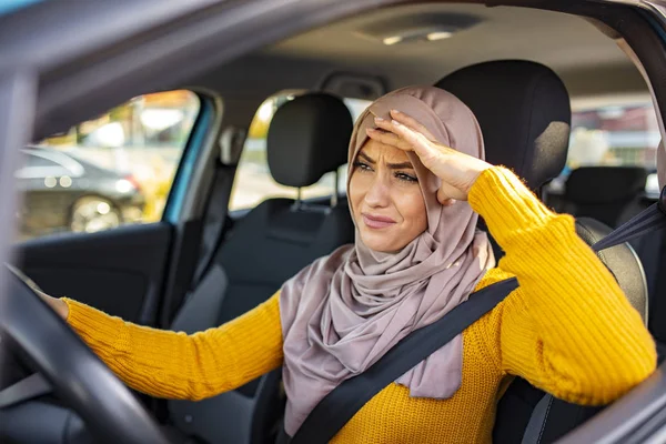 Stressed Muslim woman drive car feeling sad and angry. Distraught mid adult woman driving a car. Displeased young stressed angry pissed off woman driving car annoyed by heavy traffic