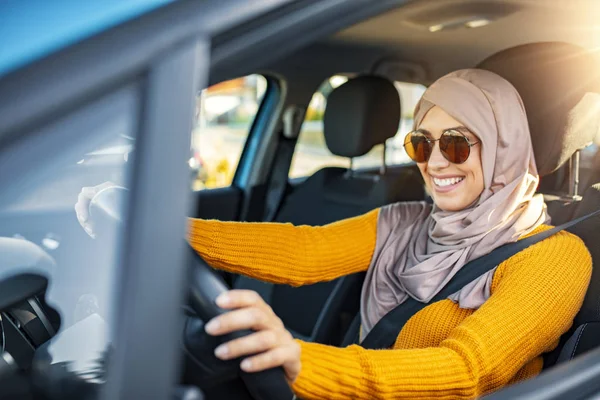 Relaxed happy Muslim woman on summer roadtrip travel vacation. Confident and beautiful. Portrait of pleasant looking female with glad positive expression, being satisfied with unforgettable journey by car, sits on driver`s seat, enjoys music