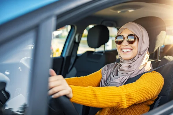 Relaxed happy Muslim woman on summer roadtrip travel vacation. Confident and beautiful. Portrait of pleasant looking female with glad positive expression, being satisfied with unforgettable journey by car, sits on driver`s seat, enjoys music