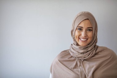 Young asian muslim woman in head scarf smile with arms crossed. Portrait of young muslim woman wearing hijab head scarf at gray background. Portrait of beautiful Muslim woman on grey background clipart