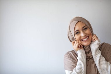 Gri arkaplanda güzel bir Müslüman kadının portresi. Gülümseyen Arap bir kadın. Sıkı bir resmi kıyafet ve şık bir görünüş. İslami moda Mükemmel ciltli Arap bir kadının profili.