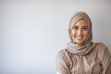 Başörtüsü gülüşlü güzel Asyalı müslüman kadın portresi. 20 'li yaşlarda, tesettürlü, gri arka planda sırıtan müslüman bir kadının portresi.. 