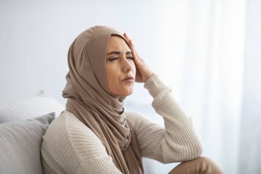Arap Suudi Emirlikleri 'nden başı ağrıyan kadın. Kötü baş ağrısı olan mutsuz genç bir kadının portresi. Şakaklarına dokunan çıplak omuzlu güzel bir müslüman kadının portresi.