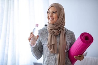 İslami kadın antrenmana hazırlanıyor. Genç Müslüman kadın koşmaya hazır. Müslüman kadın dinleniyor ve su içiyor. Müslüman kadının portresi aktif hayatı seviyor.