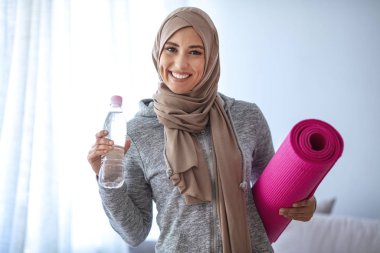 Müslüman Kadın antrenmana hazırlanıyor. Genç Müslüman kadın koşmaya hazır. Eğitimden sonra dinlenme. Spor giyim sektöründe genç, Müslüman kadın sporcu içki içiyor.