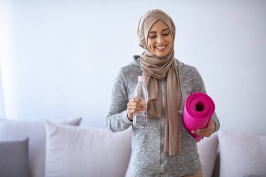 İslami kadın antrenmana hazırlanıyor. Genç Müslüman kadın koşmaya hazır. Müslüman kadın dinleniyor ve su içiyor. Genç Müslüman kadın antrenman için spor eşyaları topluyor.