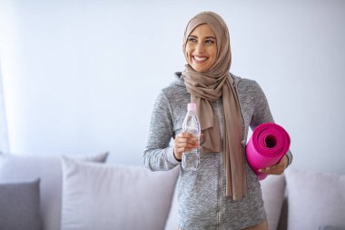 İslami kadın antrenmana hazırlanıyor. Genç Müslüman kadın koşmaya hazır. Müslüman kadın dinleniyor ve su içiyor. Genç Müslüman kadın antrenman için spor eşyaları topluyor.