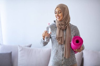 İslami kadın antrenmana hazırlanıyor. Genç Müslüman kadın koşmaya hazır. Müslüman kadın dinleniyor ve su içiyor. Müslüman kadının portresi aktif hayatı seviyor.