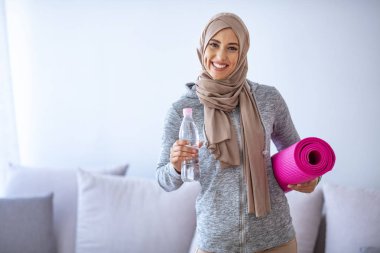 Müslüman kadın antrenmana hazırlanıyor. Genç Müslüman kadın koşmaya hazır. Müslüman kadın dinleniyor ve su içiyor. Müslüman kadının portresi aktif hayatı seviyor.