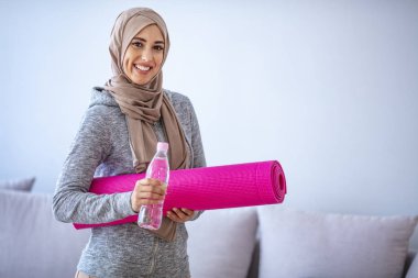 İslami kadın antrenmana hazırlanıyor. Genç Müslüman kadın koşmaya hazır. Müslüman kadın dinleniyor ve su içiyor. Genç Müslüman kadın antrenman için spor eşyaları topluyor.