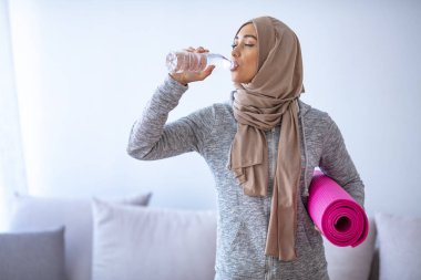 İslami kadın antrenmana hazırlanıyor. Genç Müslüman kadın koşmaya hazır. Müslüman kadın dinleniyor ve su içiyor. Müslüman kadının portresi aktif hayatı seviyor.