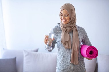 Müslüman kadın antrenmana hazırlanıyor. Genç Müslüman kadın koşmaya hazır. Müslüman kadın dinleniyor ve su içiyor. Müslüman kadının portresi aktif hayatı seviyor.