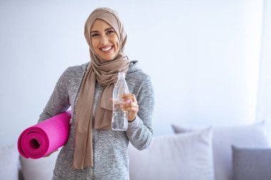 Müslüman Kadın antrenmana hazırlanıyor. Genç Müslüman kadın koşmaya hazır. Eğitimden sonra dinlenme. Spor giyim sektöründe genç, Müslüman kadın sporcu içki içiyor.
