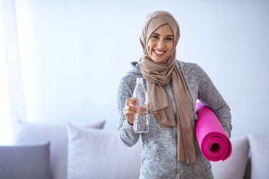 Genç Müslüman kadın su içiyor. Genç Müslüman kadın koşmaya hazır. Elinde bir şişe su ve fitne tutan genç Müslüman kadın. Müslüman kadının portresi aktif hayatı seviyor.
