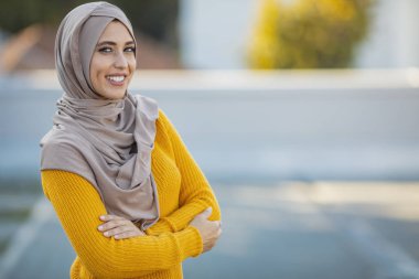 Müslüman bir kadın tesettürlü, mutlu bir yüzle ayakta duruyor ve kendine güvenen bir gülümsemeyle dişlerini gösteriyor. Gülümseyen yüzlü Müslüman kadınlar. Güzel bir orta doğu kadını abaya giyiyor.