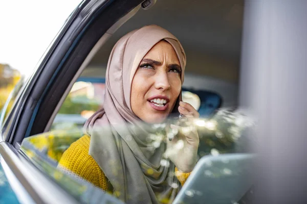 Muslim Businesswoman work with digital tablet computer and holding cup of coffee in back seat of luxury car. Beautiful business woman is using a smart phone while sitting on back seat in the car