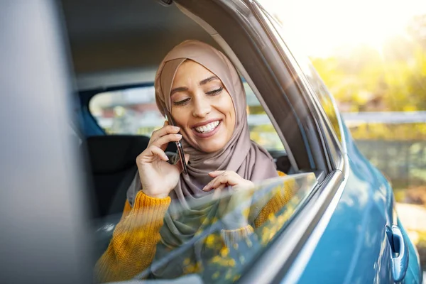 Beautiful Muslim businesswoman in car on the way to her workplace. Businesswoman using smart phone in a car. Muslim Woman using a smart phone in a car