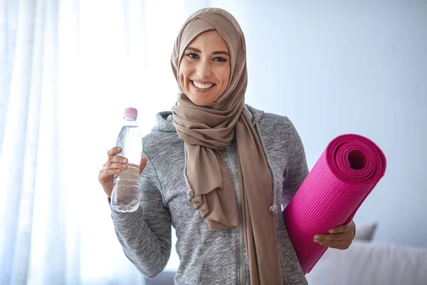 Muslim Woman getting ready for a workout. Young muslim woman ready to running. Refreshment after training.  Young sporty muslim woman athlete in sportswear drinkin