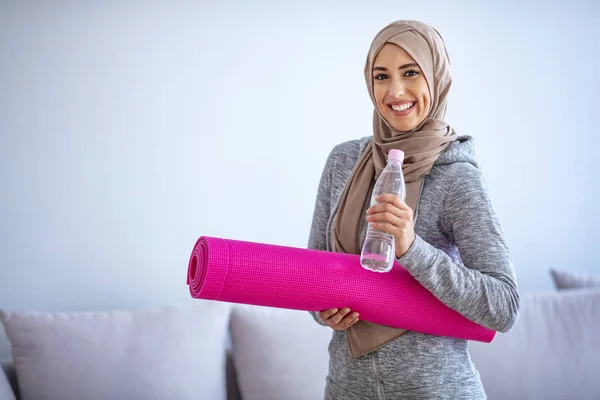 Fit young muslim woman drinking water . Young muslim woman ready to running. Young muslim woman holding bottle of water and fitnes mate. Portrait of muslim woman likes her active life