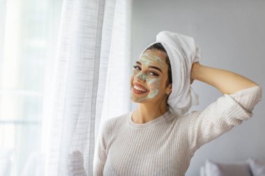 Kadın yüz derisine bakıyor. Güzel bir kadın banyodan sonra güzellik yapıyor. Yüzüne maske takan güzel bir kadın. Güzellik Tedavileri.