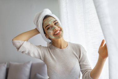 Evinde killi bir kadın ya da yüzünde çamur maskesi olan güzel bir kadın. Evde kozmetik maske takan hoş bir kadın. Cildini tazeliyor.