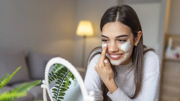 快乐的年轻女人在家里戴着面具笑着 漂亮的女性在镜子前做美容治疗 女孩使用洗涤剂 剥皮和清洁皮肤 皮肤护理 — 图库照片