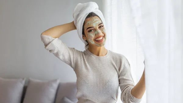 Woman aplying beauty mask,close up. Spa Woman applying Facial clay Mask. Beauty Treatments. Close-up portrait of beautiful girl with a towel on her head with facial mask.