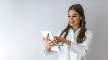 Kadın doktor hastane lobisinde tablet bilgisayar kullanıyor, gülümsüyor. Kadın doktor hastanede dikilirken tablet bilgisayar kullanıyor. Tablet bilgisayar kullanan bir kadın doktorun yakın çekimi