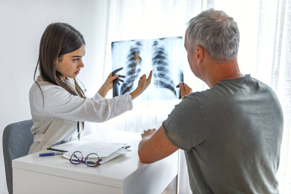 Молодой доктор разговаривает с пациенткой в ее каюте. Доктор показывает рентген пациенту. Доктор и пациент смотрят на рентген в медицинском кабинете. Доктор показал пациенту рентген грудной клетки
