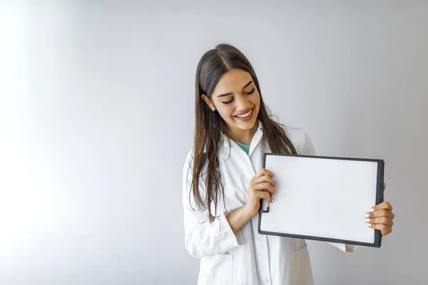 手に空白のままの幸せな医師 白い紙でクリップボードを示す女性医師 研究室のコートと空白のクリップボードを保持している女性医師のクローズアップ — ストック写真