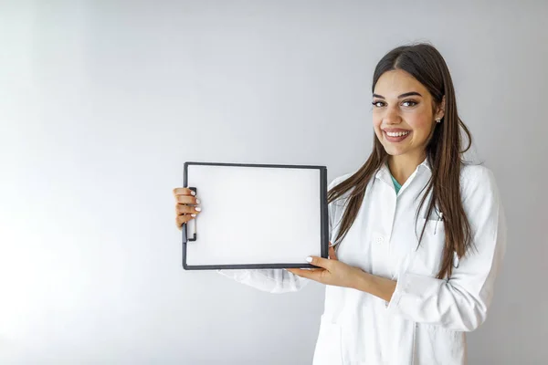 灰色の背景に隔離されたテキストやデザインのためのコピースペースとクリップボードを示す陽気な若い女性医師 診断とフォルダを示す若い幸せな笑顔の医者 — ストック写真