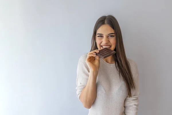 Молодая Женщина Натуральным Макияжем Весело Едят Шоколад Изолированы Сером Фоне — стоковое фото
