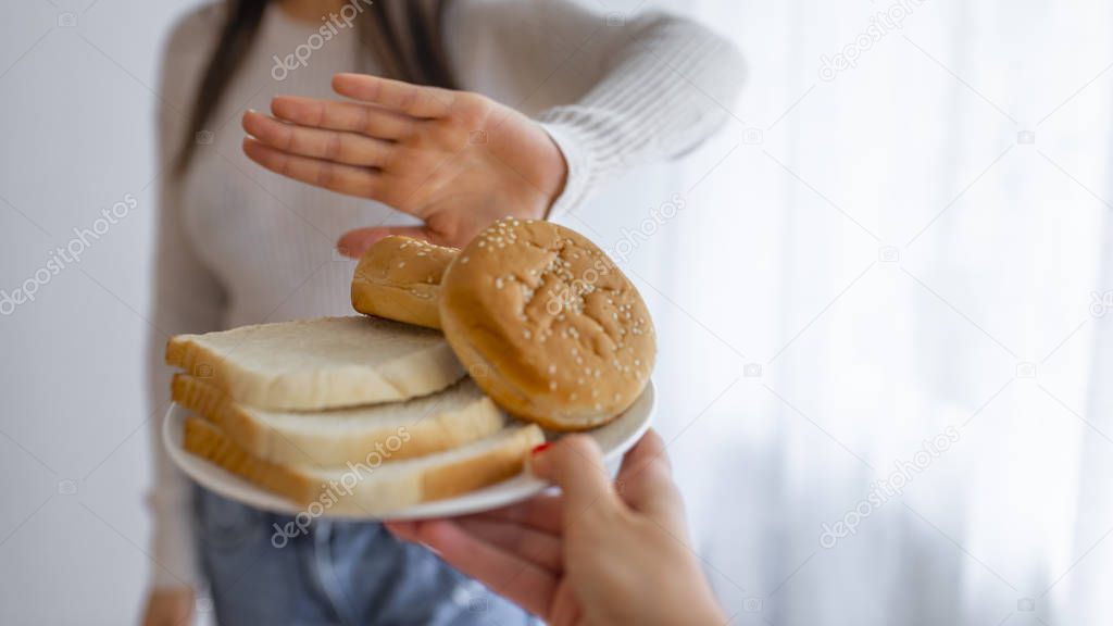 Young woman on gluten free diet is saying no thanks to toast. A woman on a gluten free diet is saying no thanks to toast. Woman refusing to eat white bread